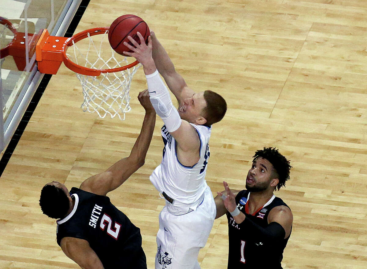 Villanova's Donte DiVincenzo, center, dunks between Texas Tech's Zhaire Smith, left, and Brandone Francis during the second half of an NCAA men's college basketball tournament regional final, Sunday, March 25, 2018, in Boston.