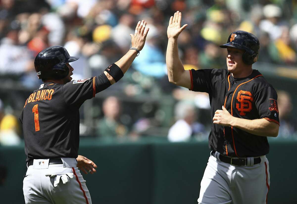 San Francisco Giants' Gregor Blanco, left, and Nick Hundley celebrate after scoring against the Oakland Athletics during the third inning of a spring training baseball game on Sunday, March 25, 2018 in Oakland, Calif. Both scored on a double by Giants' Buster Posey. (AP Photo/Ben Margot)
