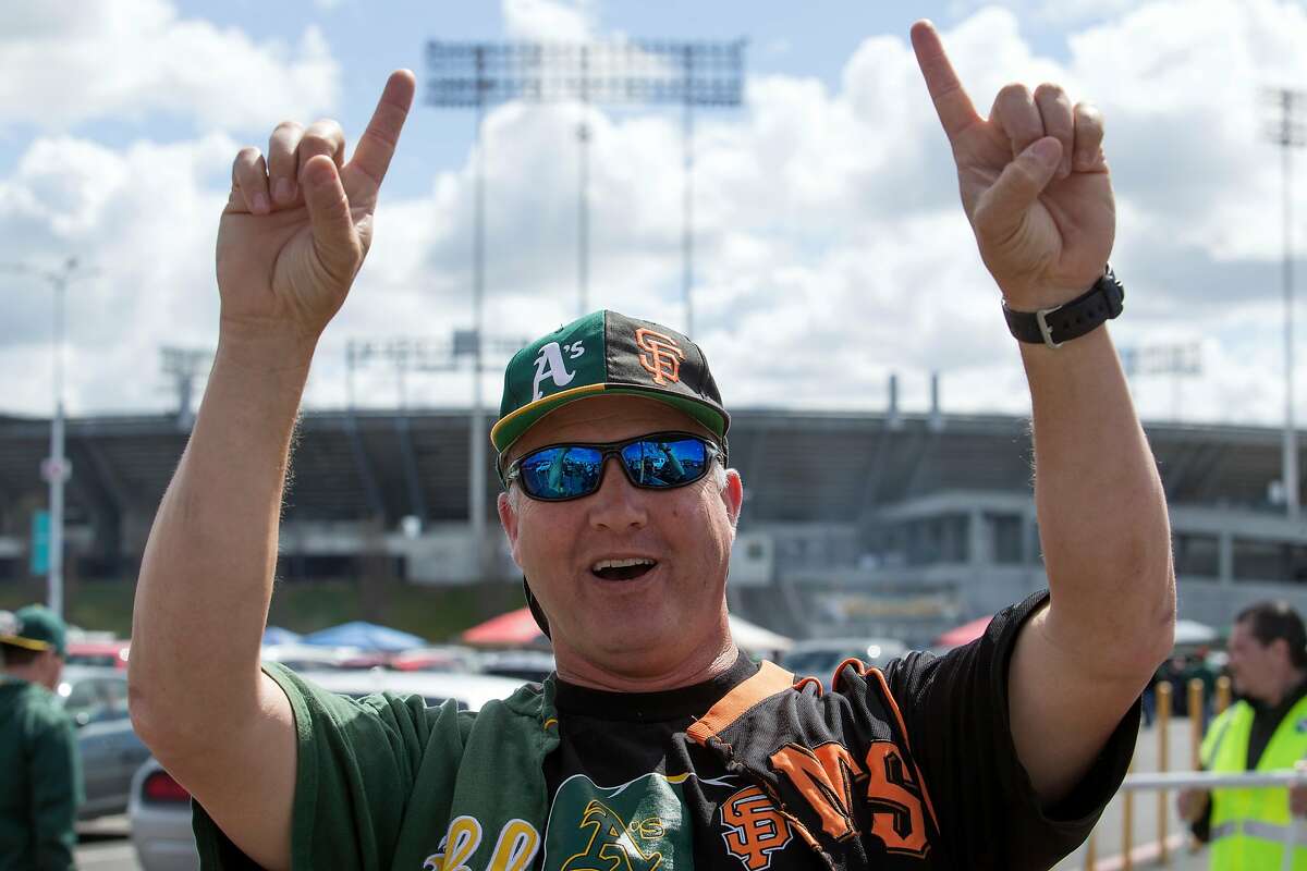 Jeff Kehr of San Ramon, Calif., whose loyalties are obvious split between the Oakland Athletics and San Francisco Giants, tailgates before a the first game of the Bay Bridge Series, Sunday, March 25, 2018 in Oakland, Calif.