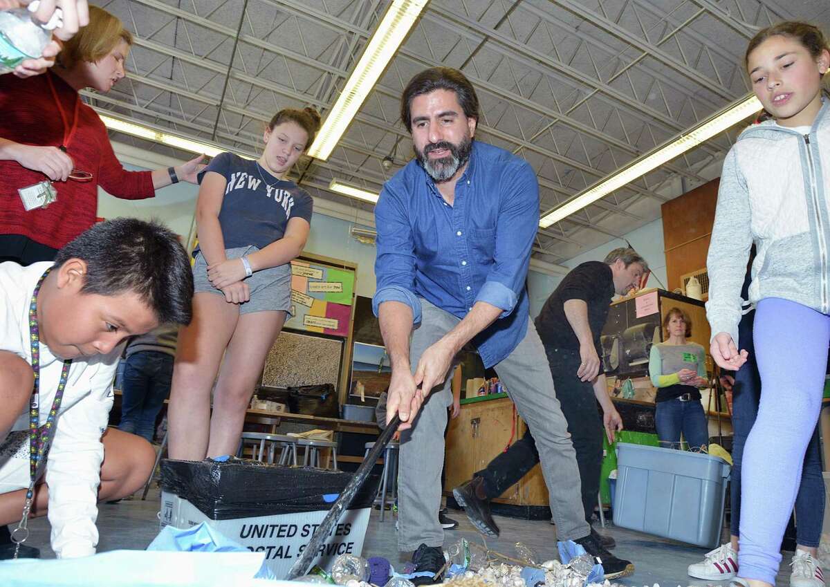 Eastern Middle School sixth grade students with the help of visiting environmental artists, Willie Cole and Alejandro Duran, pictured here at center, created their "Message in a Bottle" art project using plastic pollution and other discarded items collected from Tod's Point during class at the school in Greenwich, Conn., Friday, March 23, 2018.
