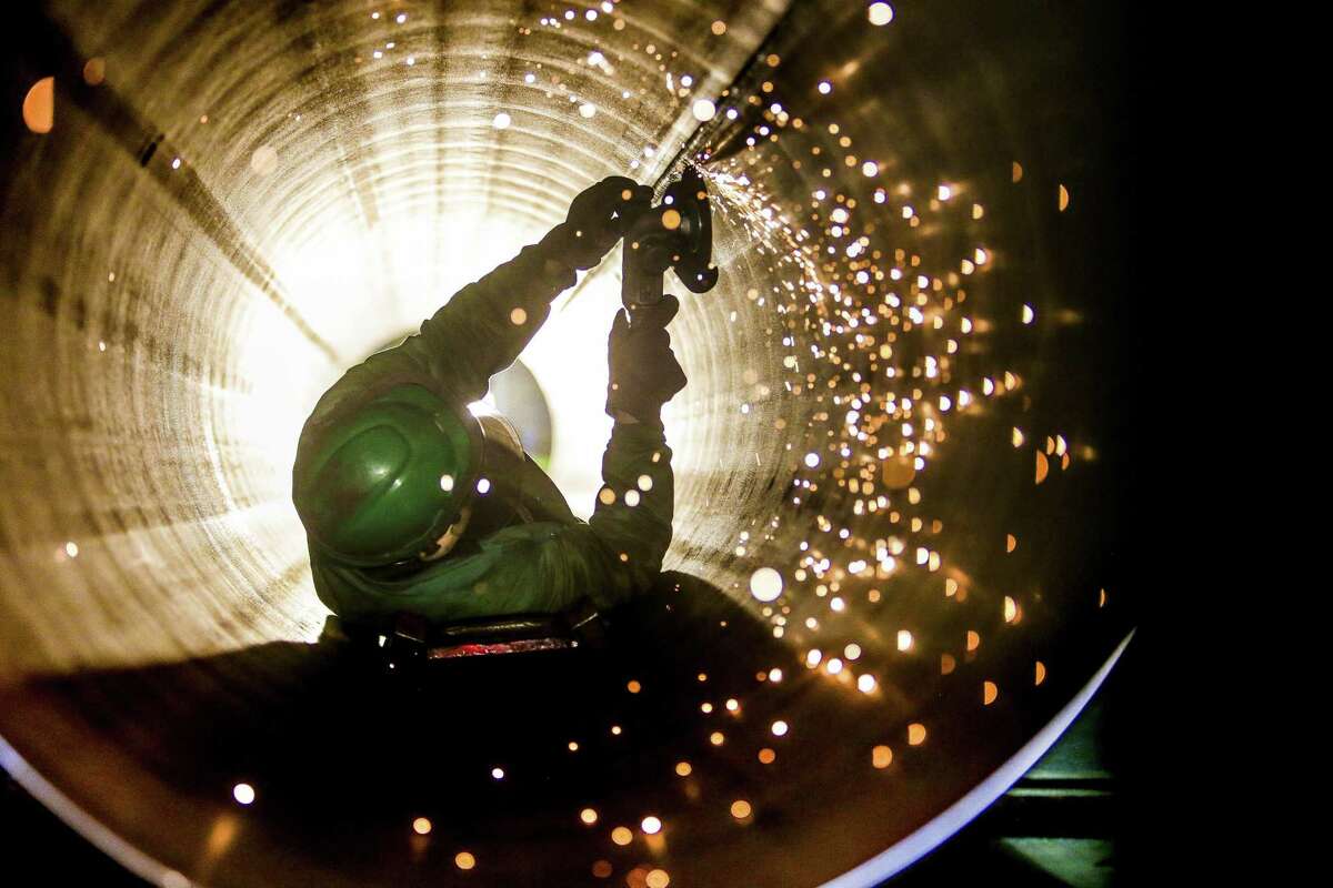 A JSW Steel employee uses a grinder to smooth out the inside of a steel pipe.