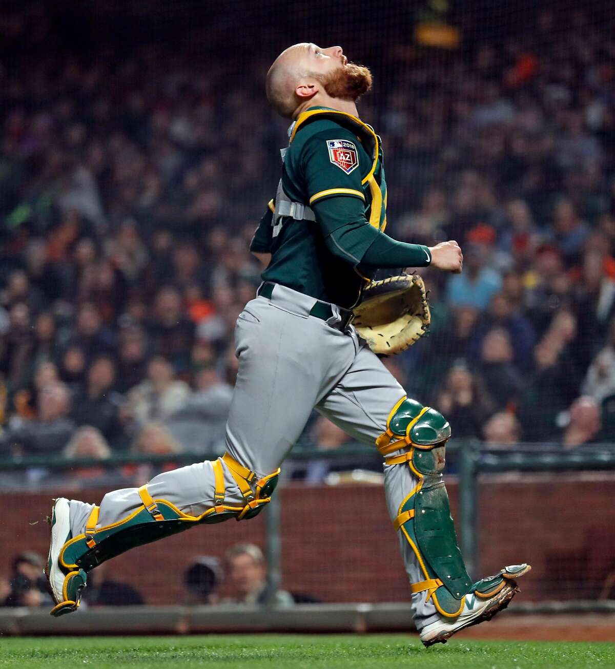 Oakland Athletics' Jonathan Lucroy tracks a pop up off the bat of San Francisco Giants' Buster Posey in 3rd inning during Bay Bridge Series game at AT&T Park in San Francisco, Calif., on Monday, March 26, 2018.