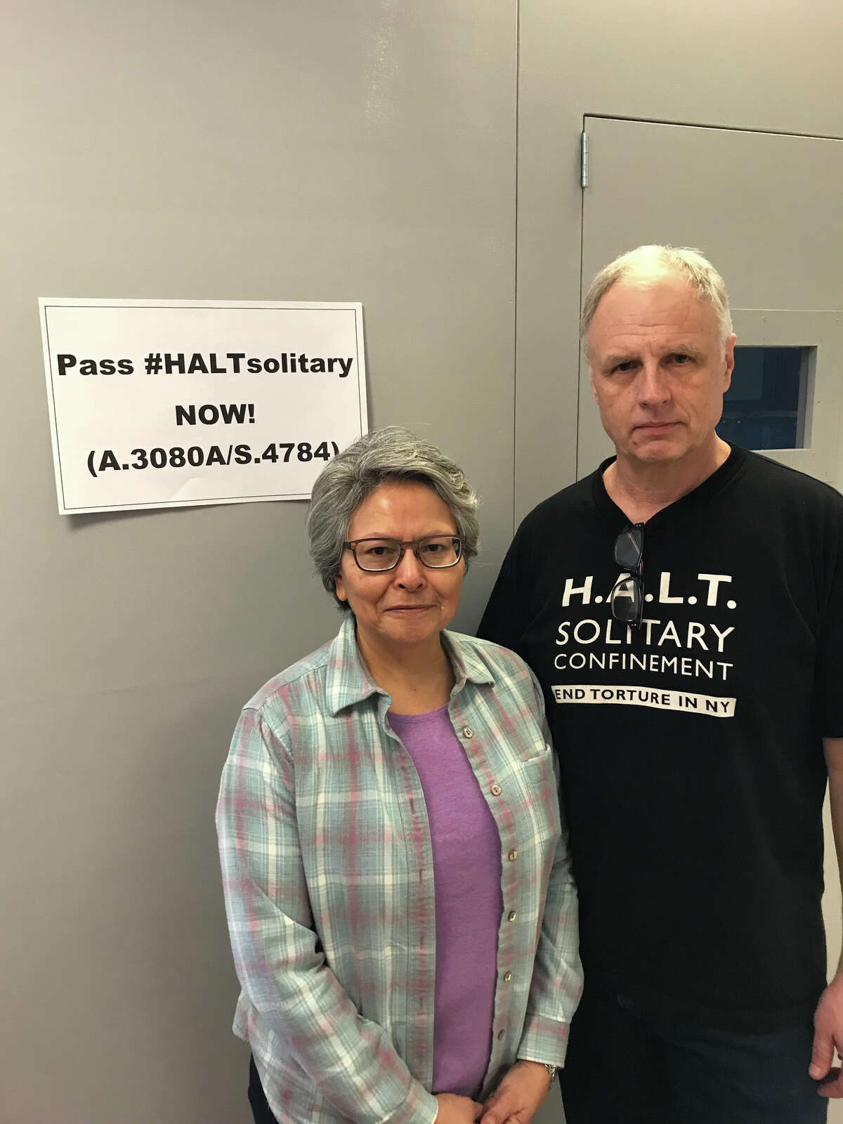 Alicia Barraza, left, and her husband, Douglas Van Zandt, in front of a replica solitary confinement prison cell he built to urge prison cell after his 21-year-old son Ben hung himself in a solitary cell