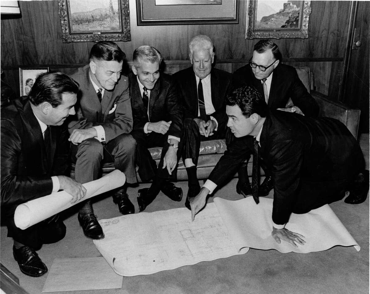 Jamaica Corp. president Welcome Wilson (kneeling on the blueprints) explains a project to multi-millionaire R.E. (Bob) Smith for his approval in 1966. From left are: Welcome’s brother, Jack Wilson, Eugene Maier, Johnny Goyen, Smith and Sherwood Crane. They are in Smith’s office.