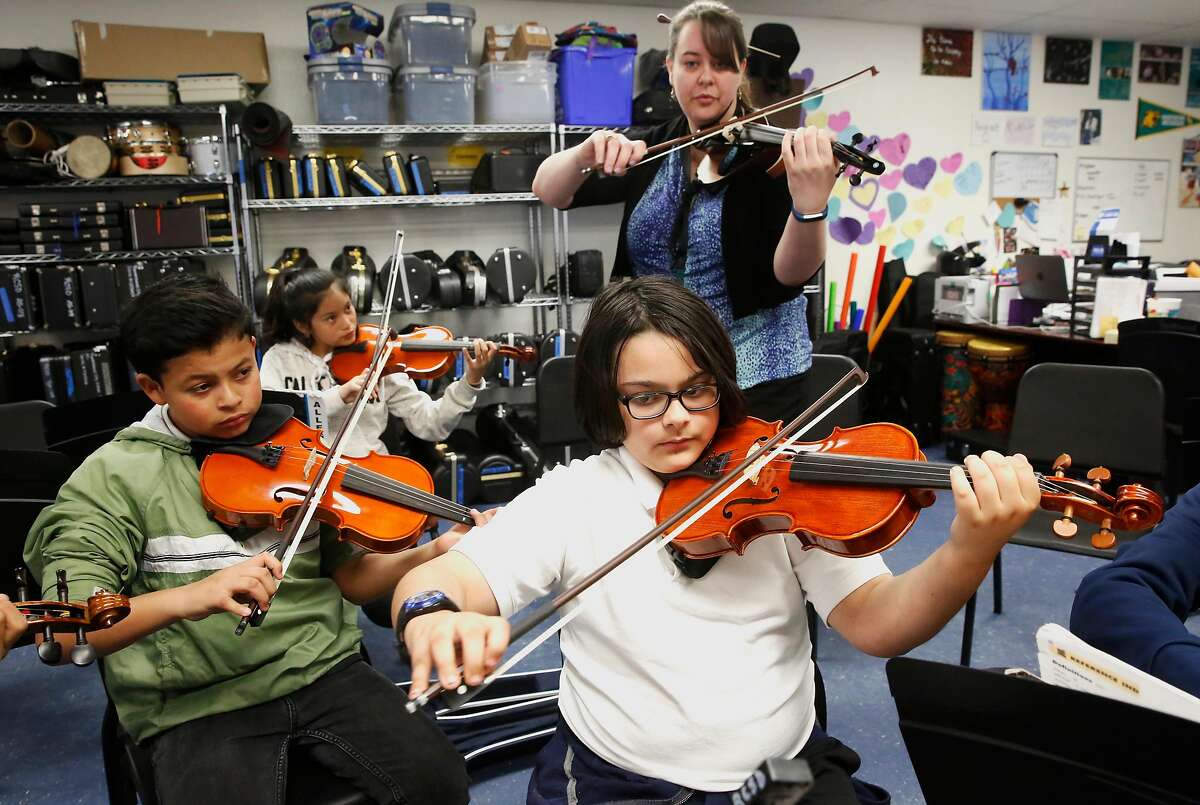 ( l to r ) Daniel Valdizon, Yareli Perez and Jason Carvalho under the guidance of Sarah Moulder as she leads her 6th grade string orchestra students at Ravenswood Middle School in East Palo Alto, Calif. as seen on Tues. Mar. 27, 2018.