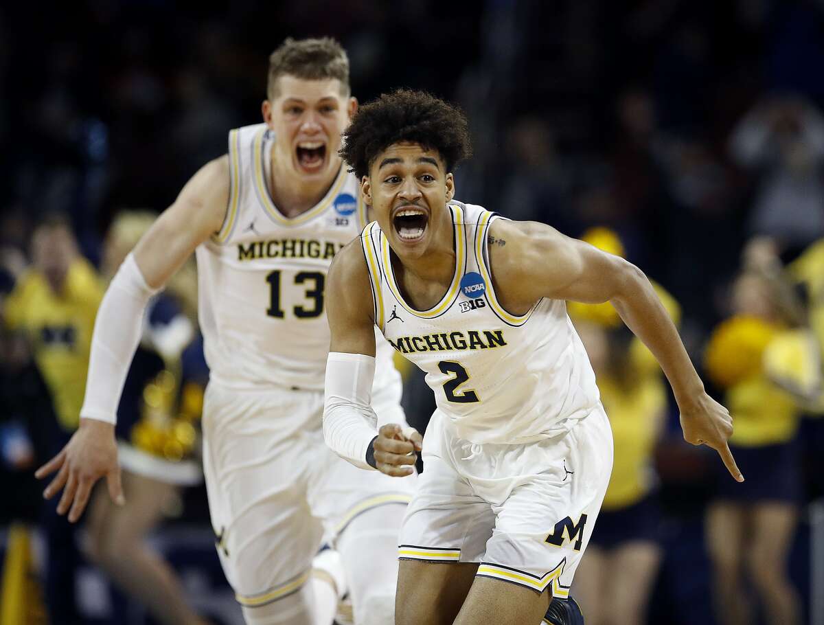 Michigan guard Jordan Poole (2) is chased by forward Moritz Wagner (13) after making a 3-point basket at the buzzer to win an NCAA men's college basketball tournament second-round game against Houston on Saturday, March 17, 2018, in Wichita, Kan. Michigan won 64-63. (AP Photo/Charlie Riedel)