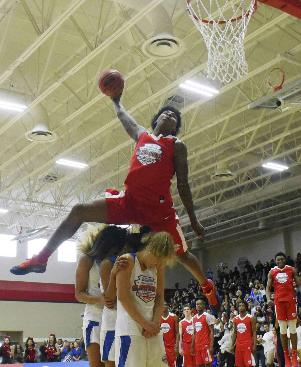 Kevin Porter jumps over three people on a dunk during the American Family Insurance Slam Dunk and 3-Point Championships at Wagner High School on Tuesday, March 27, 2018. The contest coincides with the NCAA Final Four in San Antonio.