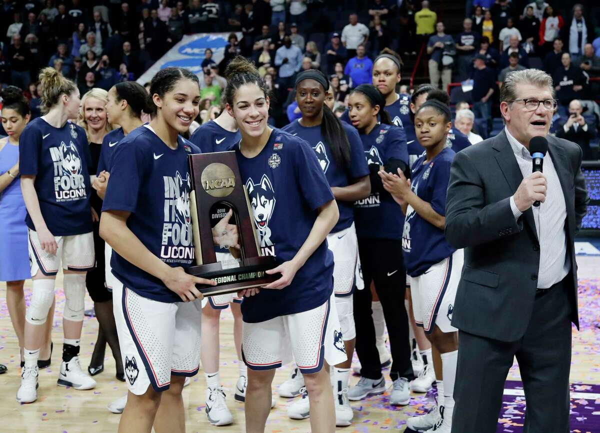 Connecticut's Gabby Williams, left, and Kia Nurse, center, hold the regional championship trophy as head coach Geno Auriemma, right, speaks after a regional final against South Carolina at the women's NCAA college basketball tournament Monday, March 26, 2018, in Albany, N.Y. (AP Photo/Frank Franklin II)