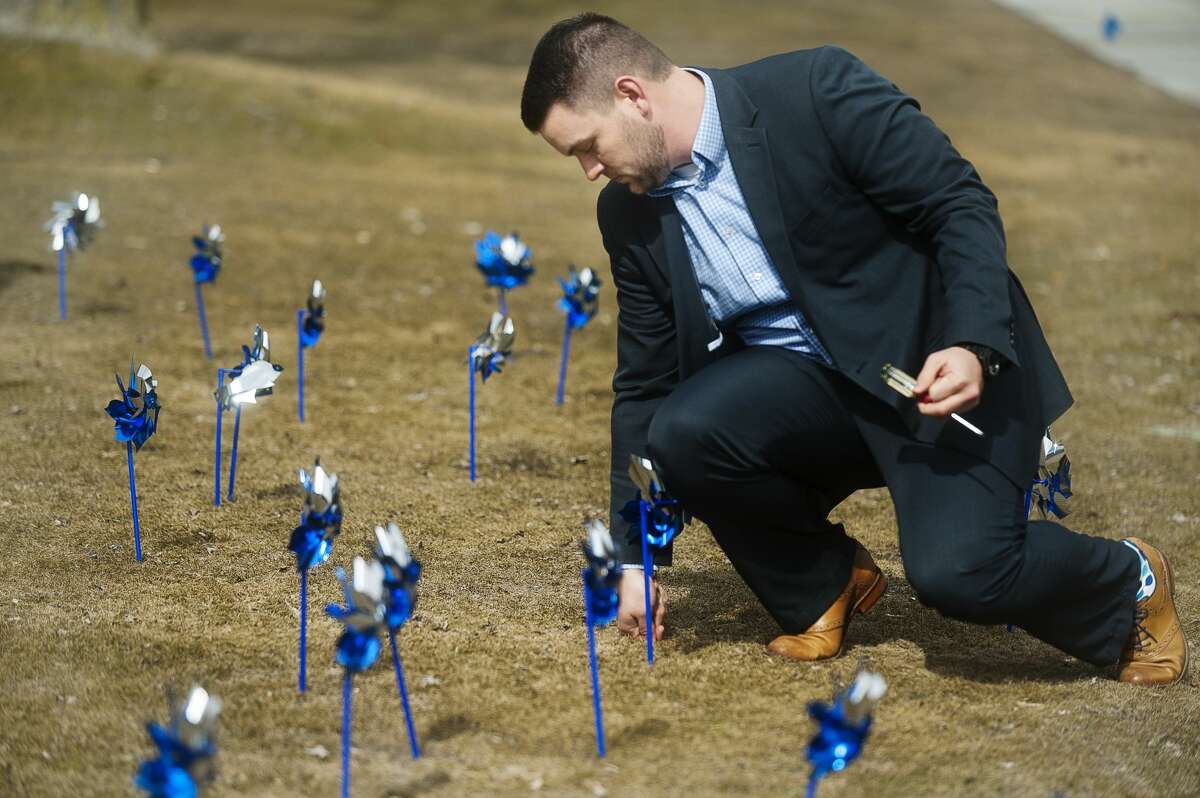 Coty Gould of Midland sticks a pinwheel into the ground in front of the Midland County Courthouse during a pinwheel ceremony on Wednesday, March 28, 2018 in honor of Child Abuse Prevention Month, celebrated every April. (Katy Kildee/kkildee@mdn.net)