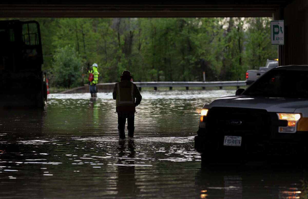 Crews work to move construction equipment off the road that is under the U.S. 59 overpass as the west fork of the San Jacinto River overflowed Thursday, March 29, 2018, in Humble, Texas.