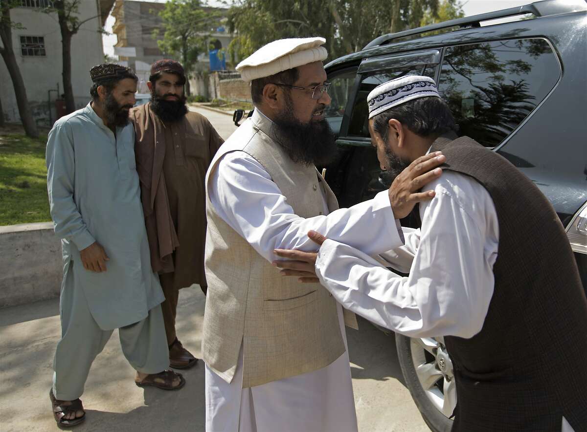 In this Thursday, March 22, 2018 photo, Pakistani militant leader Fazlur Rehman Khalil, center, greets visitors at his compound in Islamabad, Pakistan. Khalil, whose group Harakat-ul-Mujahedeen, now known as Ansar-ul Ummah, is on the US designated terrorist list, tells of a fatwa he helped craft outlawing violent militancy in Pakistan. Yet just his mere presence on the outskirts of the Pakistan capital has analysts questioning Pakistan�s readiness to rout militants and their followers from its territory. (AP Photo/B.K. Bangash)