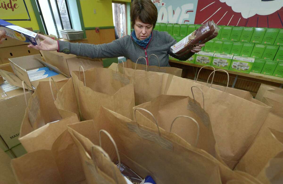 Volunteers from the First Congregational Church in Darien including Caroline Burke put together bags of food for Easter at the Open Door Shelter Thursday in Norwalk. The shelter distributed food for Easter, as spring is still a time of need for food pantries, but the Easter holiday is less on people’s radar as a day of giving than winter holidays such as Thanksgiving and Christmas.