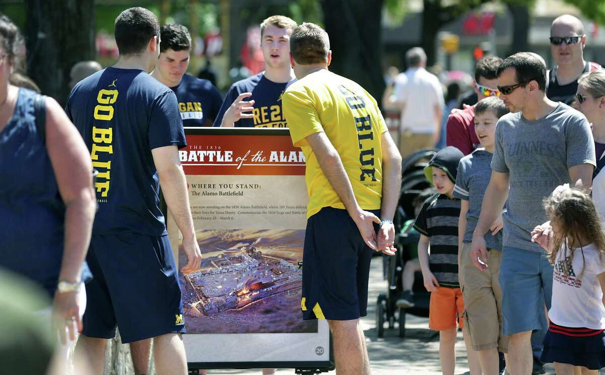 Members of the Michigan team managers stop to read an information board about the Battle of the Alamo in Alamo Plaza as Final Four fans crowd the downtown streets and Riverwalk on Thursday, March 29, 2018.