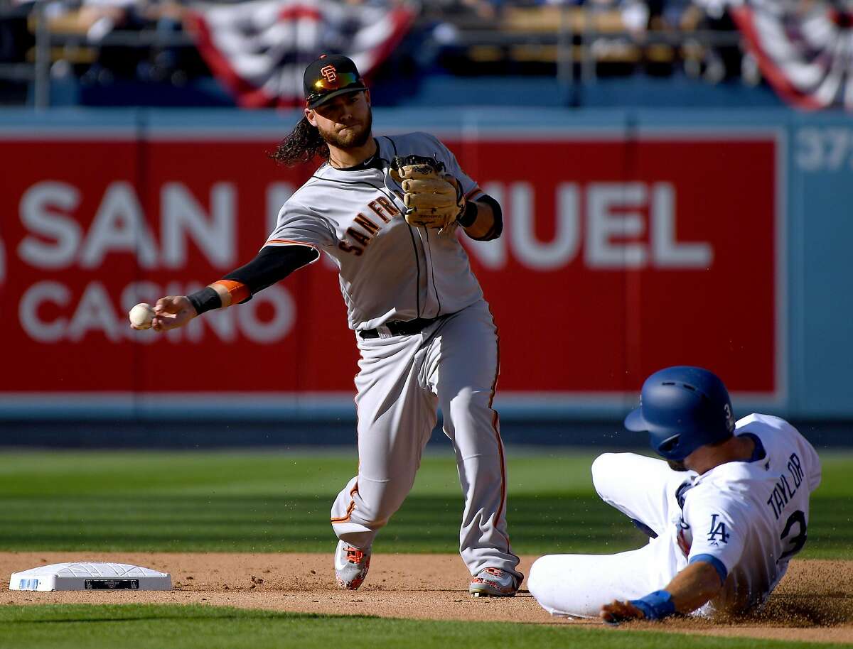 Brandon Crawford #35 of the San Francisco Giants turns a double play over Chris Taylor #3 of the Los Angeles Dodgers during the third innning on the 2018 Major League Baseball opening day at Dodger Stadium on March 29, 2018 in Los Angeles, California.