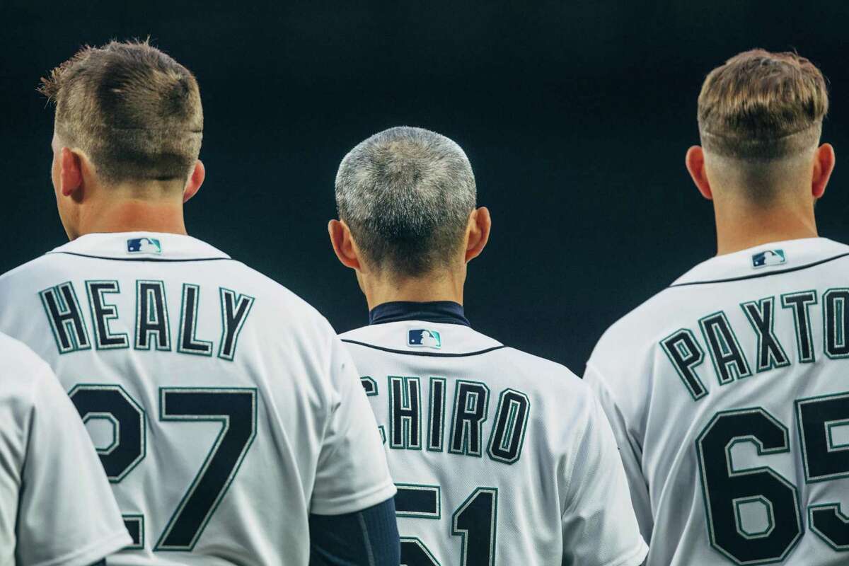 Mariners outfielder Ichiro Suzuki stands between first baseman Ryon Healy and pitcher James Paxton, during the national anthem on opening day 2018 at SafeCo Field on Thursday, March 29, 2018. Suzuki, 44, returned to the Mariners after playing for them for 12 years beginning in 2001.