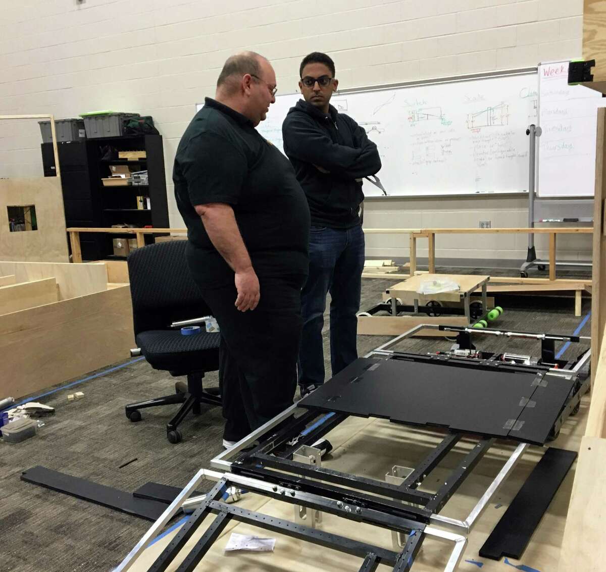 David Scarcella, an instructor with the Pasadena Independent School District, and Josh Sooknanan, a robotics engineer with NASA, discuss a prototype robot built by the district's FIRST Robotics Team High Voltage. Scarcella coaches and Sooknanan mentors high school students participating in a worldwide competition involving 3,400 teams. The global championship will be held in Houston.