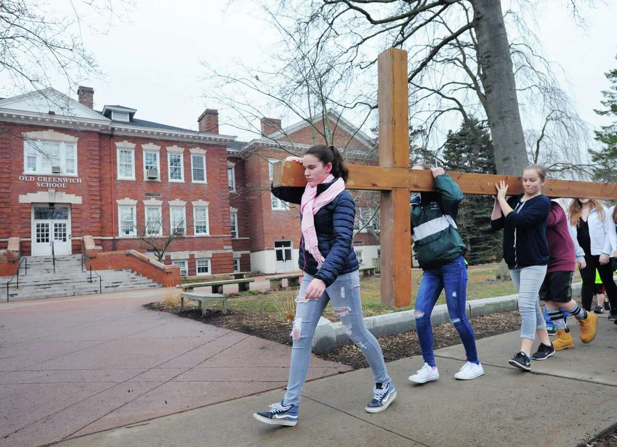 At left, Elizabeth Mohn of the First Congregational Church of Greenwich Youth Group leads the group's cross walk past the Old Greenwich School, Old Greenwich, Conn., Good Friday, March, 30, 2018.