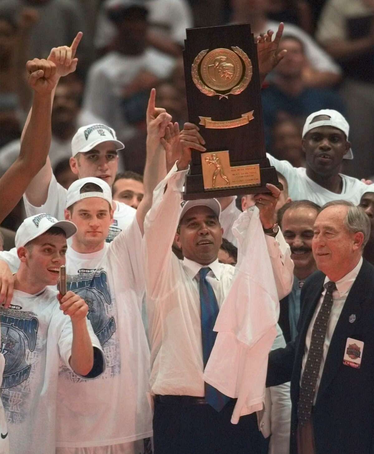 Kentucky coach Tubby Smith holds up the NCAA Div. I Championship trophy after the Wildcats 78-69 beat Utah in the NCAA Men's Final Four Championship game, Monday, March 30, 1998, at the Alamodome in San Antonio. At right is C.M. Newton, Kentucky atheletic director. (AP Photo/L.M. Otero)