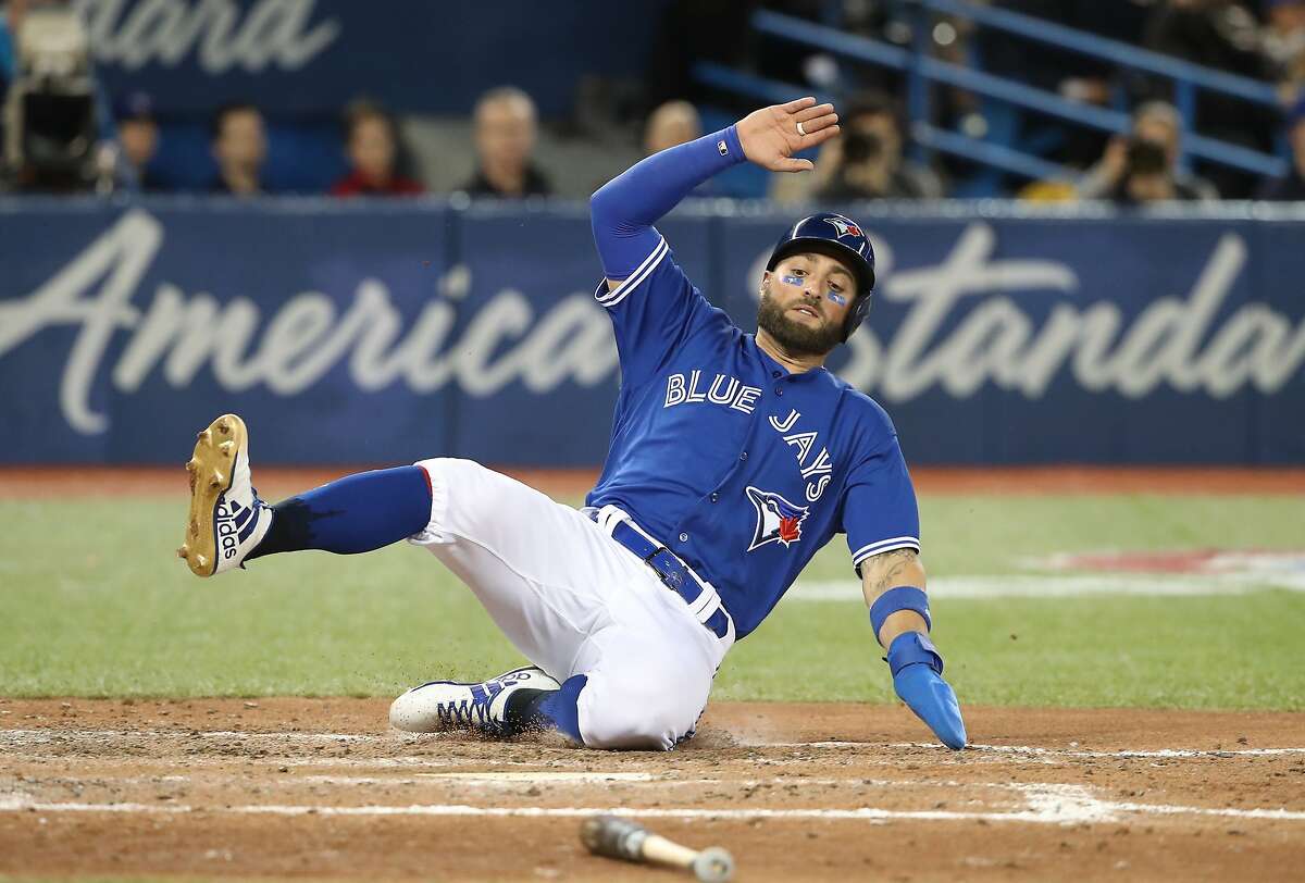 TORONTO, ON - MARCH 31: Kevin Pillar #11 of the Toronto Blue Jays slides across home plate to score a run in the sixth inning on an RBI single by Luke Maile #21 during MLB game action against the New York Yankees at Rogers Centre on March 31, 2018 in Toronto, Canada. (Photo by Tom Szczerbowski/Getty Images)