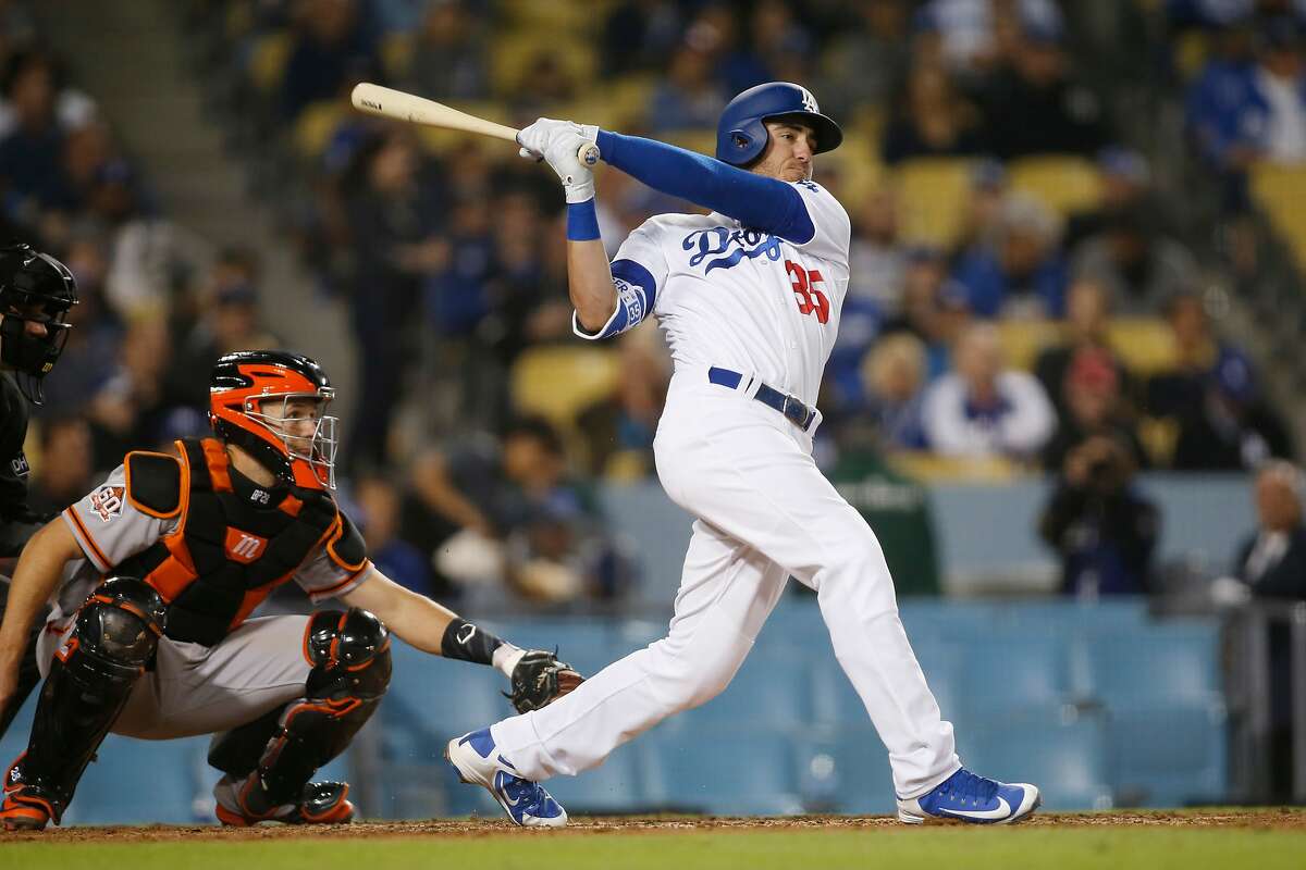 Los Angeles Dodgers' Cody Bellinger singles in front of San Francisco Giants' Buster Posey during the eighth inning of a baseball game Sunday, April 1, 2018, in Los Angeles. (AP Photo/Danny Moloshok)