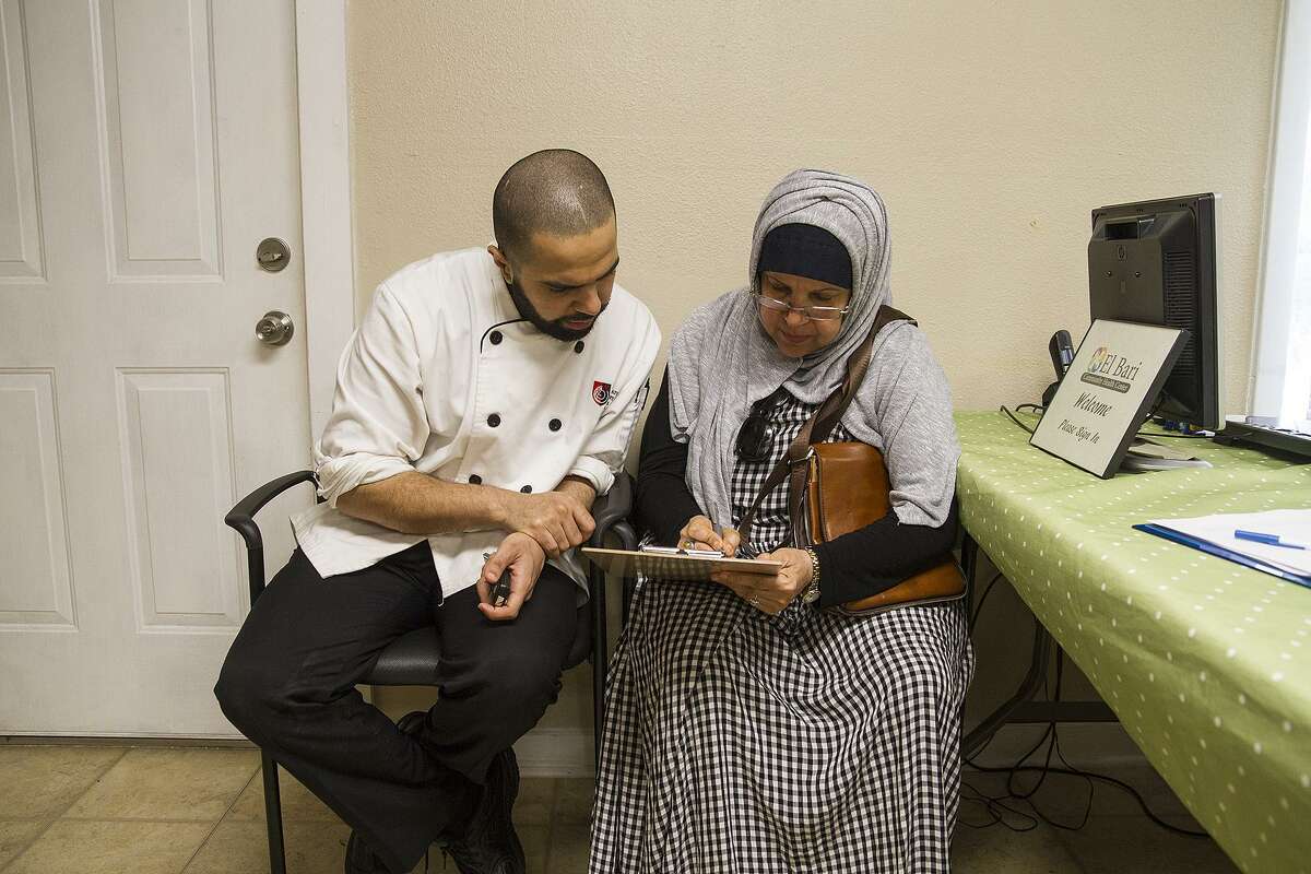 Mohammad Aldrees helps his mother, Khatoon Taher, fill out new paperwork at the clinic near De Zavala Road and Interstate 10.