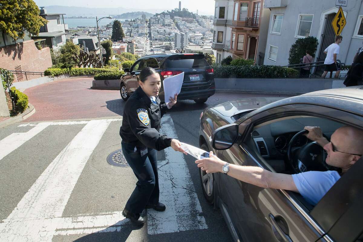 SFPD cadet Jessica Banuelos passing out flyers to help convince everybody to leave nothing in their cars on Lombard Street on Monday, April 2, 2018 in San Francisco, CA.