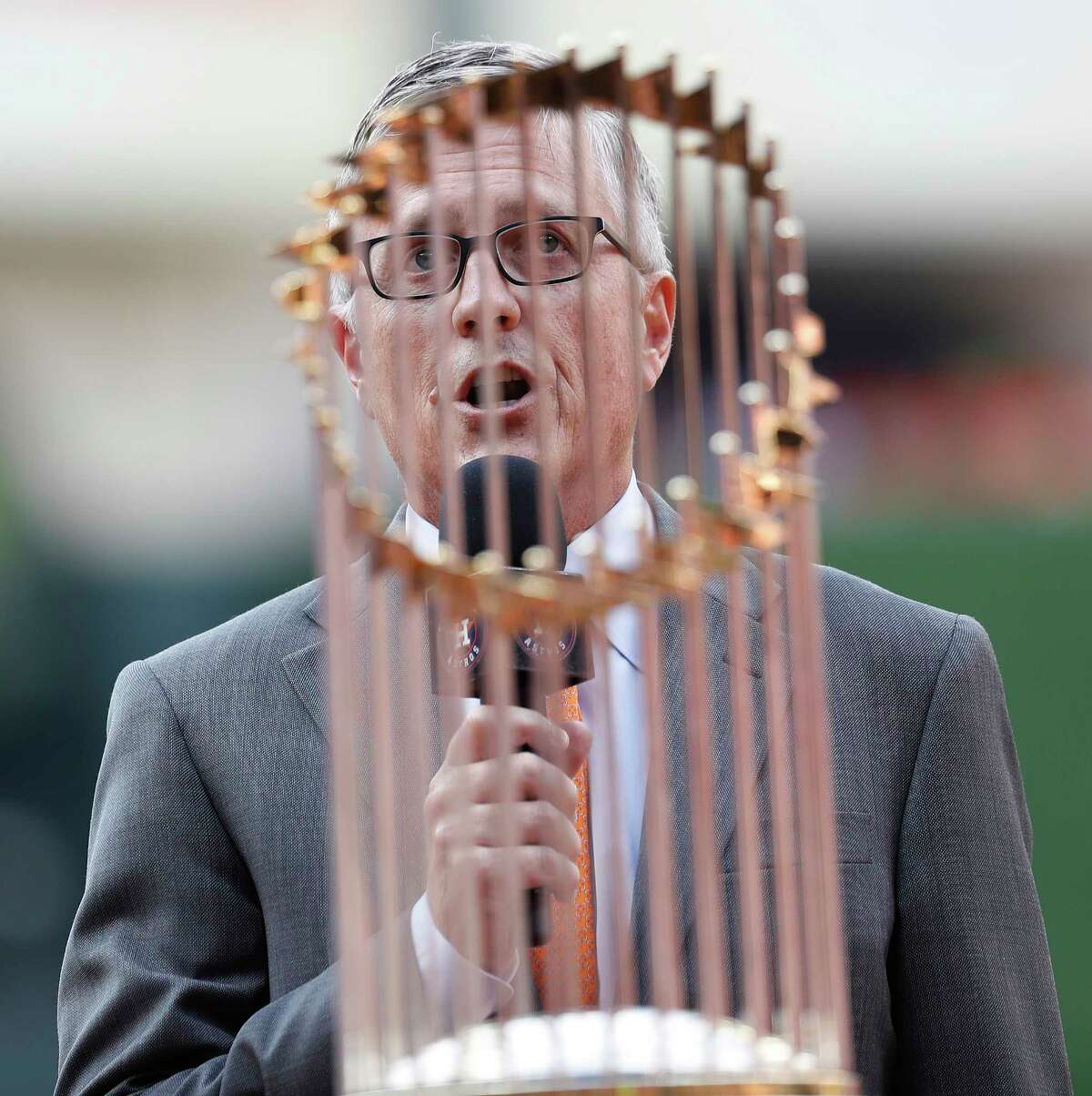 Houston Astros GM Jeff Luhnow speaks to the fans behind the World Series trophy during the pre-game ceremony before the start of the home opener during an MLB baseball game at Minute Maid Park, Monday, April 2, 2018, in Houston.