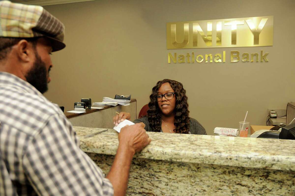 Jesse Lamb is helped at the counter by teller Earleisha Ryan at the Unity National Bank on Blodgett Monday April 2,2018. (Dave Rossman Photo)