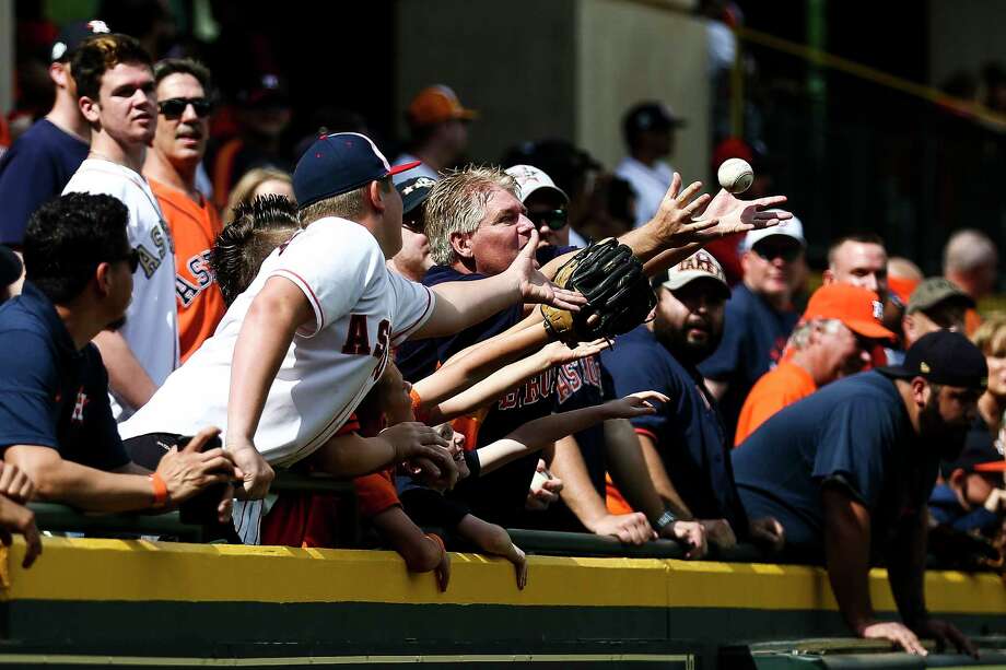Fans reach through a sea of hands for a ball tossed up into the Crawford Boxes during batting practice. Photo: Michael Ciaglo / Michael Ciaglo