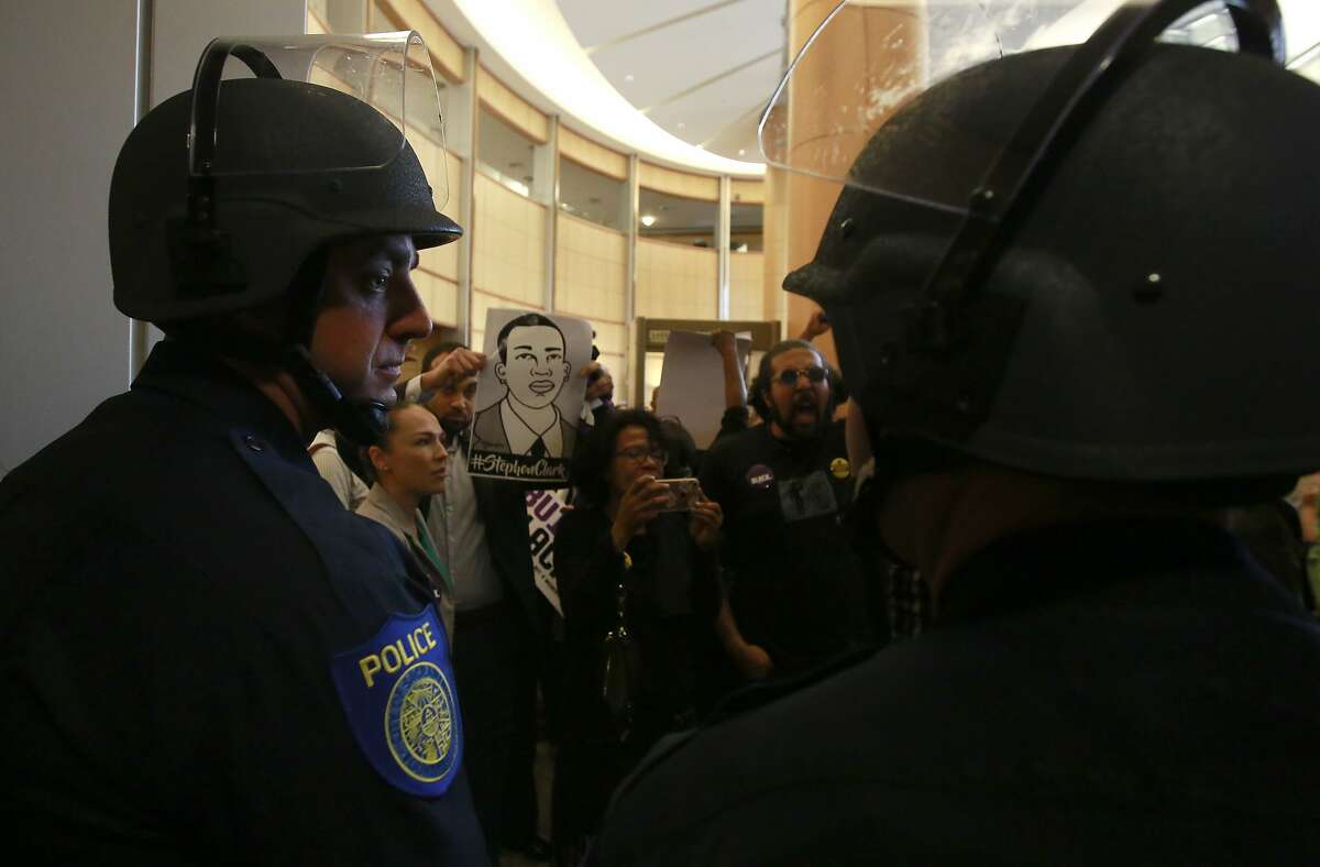 File -In this March 27, 2018, file photo, helmeted Sacramento police officers block the entrance to the Sacramento City Council chambers from demonstrators protesting the shooting death of Stephon Clark by Sacramento Police, in Sacramento, Calif. Sacramento Police Chief Daniel Hahn, the city's first black police chief, is an unlikely officer, growing up in a tough neighborhood of California's capital city and having his own early run-ins with police. He is struggling to find the right balance of reforms after the fatal shooting of Clark by his officers. (AP Photo/Rich Pedroncelli, File)
