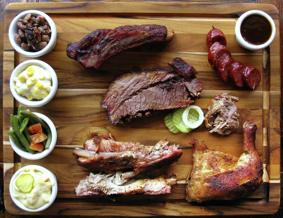 Barbecue and sides from Augie's Alamo City BBQ Steakhouse. Clockwise from bottom left: mac and cheese, green beans, creamed corn, brisket beans, beef rib, sausage, barbecue sauce, pulled pork, smoked chicken, pork spare ribs and brisket.