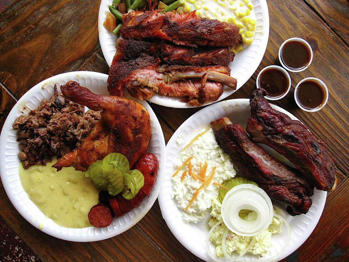 Clockwise from bottom left: three-meat plate with sausage, chicken and pulled pork with brisket beans and mac and cheese, a pork rib plate with green beans and creamed corn and a beef rib plate with cole slaw and potato salad from Augie's Alamo City BBQ Steakhouse.