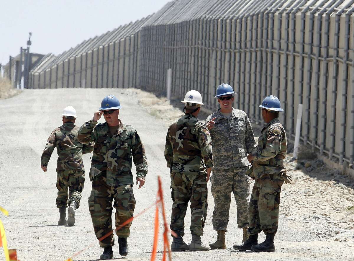 FILE - In this June 21, 2006, file photo, members of the California National Guard work next to the U.S.-Mexico border fence Wednesday, June 21, 2006, near the San Ysidro Port of Entry in San Diego. President Donald Trump said April 3, 2018, he wants to use the military to secure the U.S.-Mexico border until his promised border wall is built. The Department of Homeland Security and White House did not immediately respond to requests for comment. At the Pentagon, officials were struggling to answer questions about the plan, including rudimentary details on whether it would involve National Guard members, as similar programs in the past have done. But officials appeared to be considering a model similar to a 2006 operation in which former President George W. Bush deployed National Guard troops to the southern border in an effort to increase security and surveillance.(AP Photo/Denis Poroy, File)