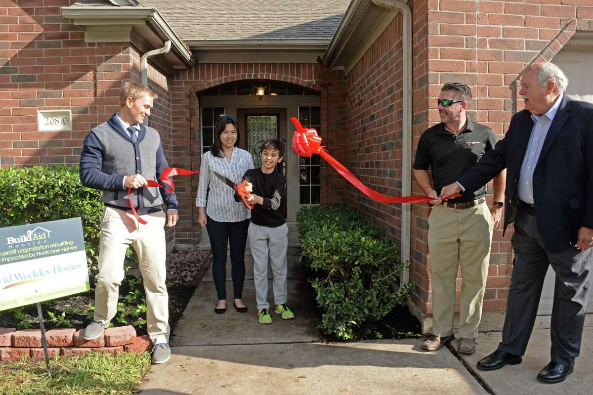 Homeowner Olivia Thornton and her son Christopher cut a ribbon at the HomeAid Welcome Home Ceremony in Katy, TX on Wednesday, April 4, 2018. Also pictured are Chris Yuko, Director of BuildAid Houston, far left, plus Randy Rowlett and David Weekley of David Weekley Homes, right.