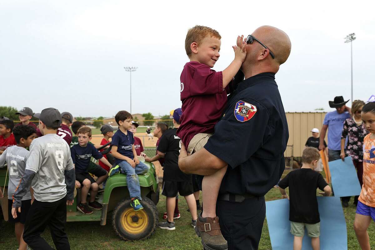 Ryland Ward, 6, plays with Stockdale Assistant Fire Chief Rusty Duncan after Duncan threw out the first pitch for the Floresville High School baseball game at the school on Tuesday, April 3, 2018.