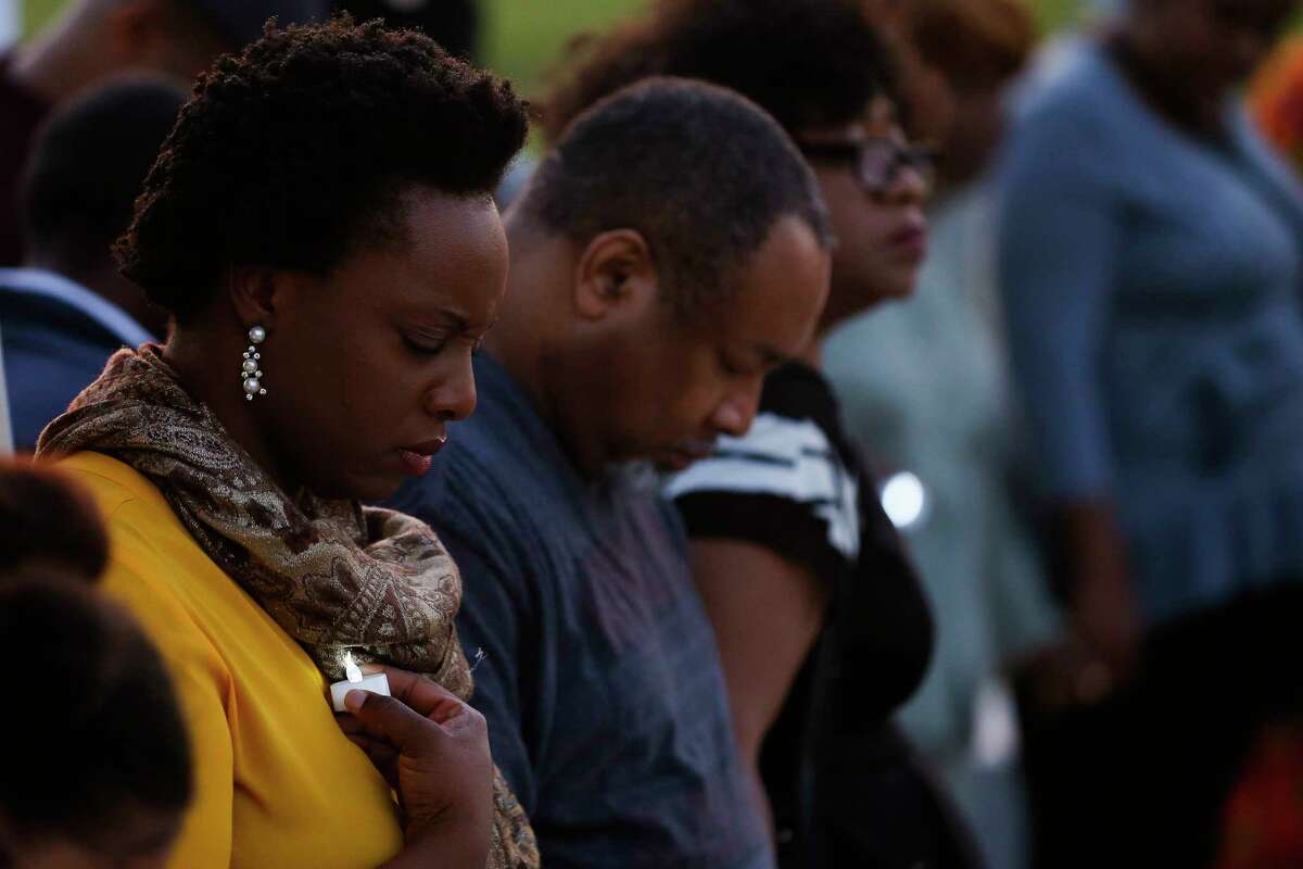 People pray the Black Heritage Society's 50th Annual Candlelight Vigil commemorating the death of Rev. Martin Luther King Jr. at MacGregor Park Wednesday, April 4, 2018 in Houston.