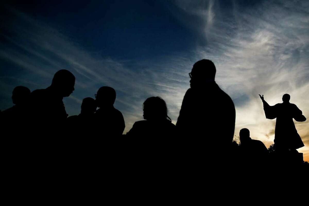 A statue of Rev. Martin Luther King Jr. is silhouetted against the evening sky as people attend the Black Heritage Society's 50th annual Candlelight Vigil at MacGregor Park Wednesday, April 4, 2018 in Houston.