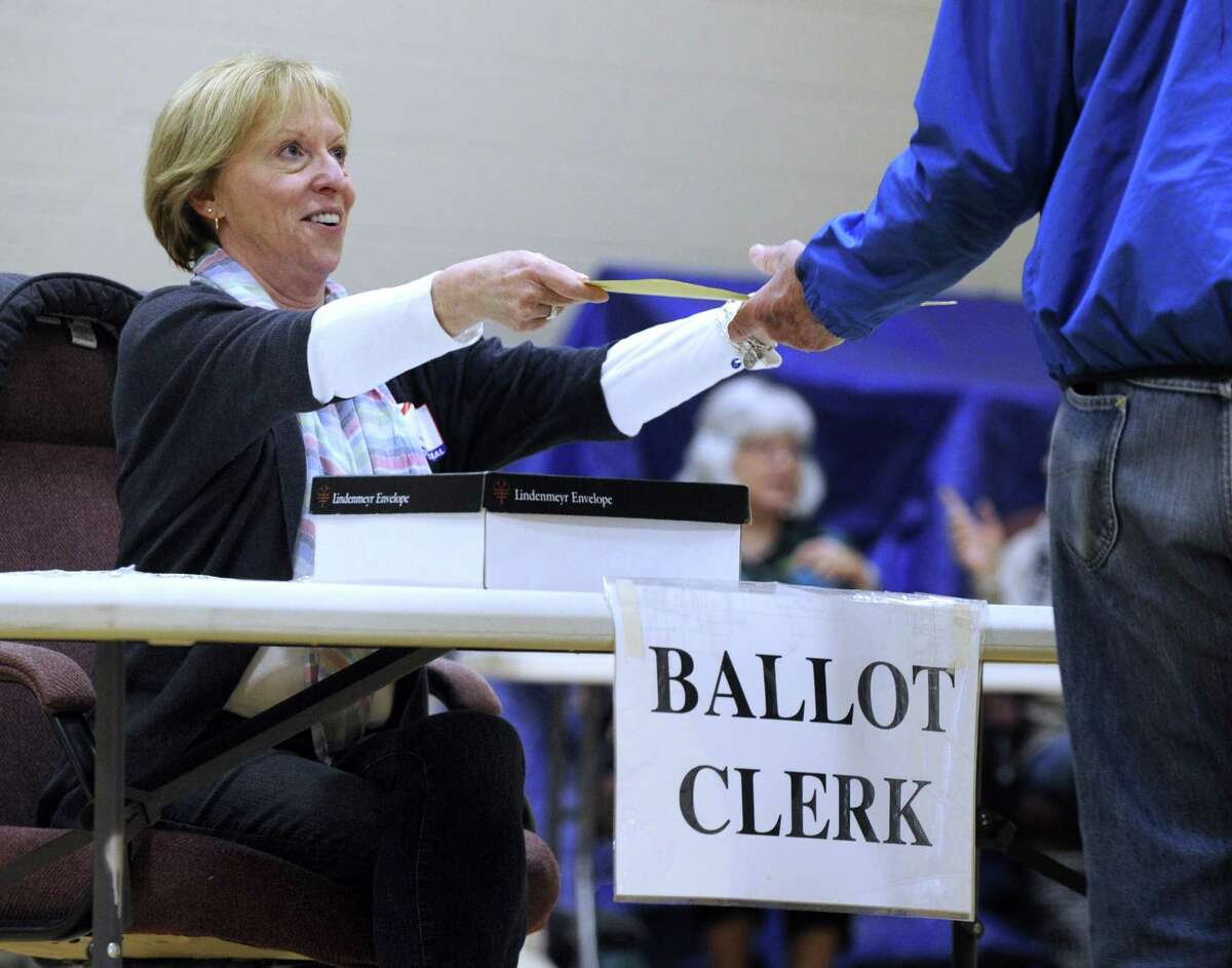 Ballot Clerk Gail Cowan hands out ballots at the Bethel Municipal Center Tuesday, April 12, 2016. Residents are voting in a budget referendum.
