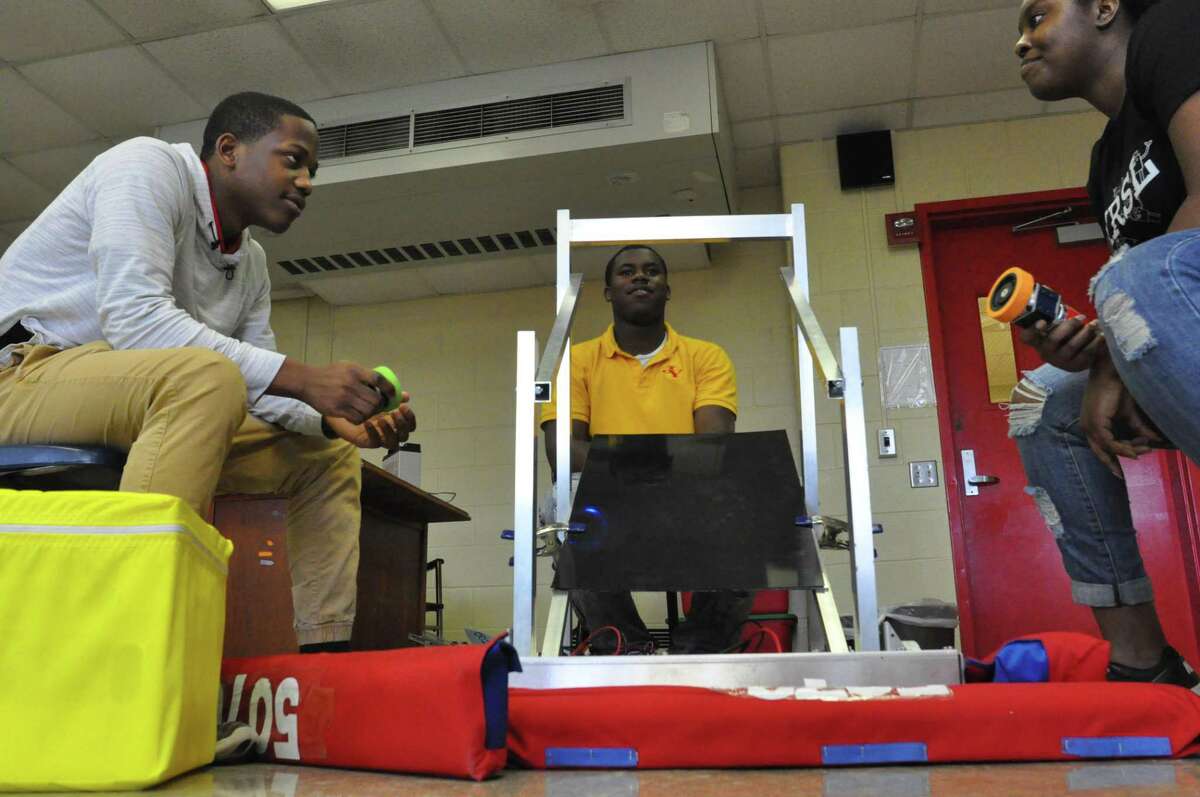 Yates High School robotics team members Rashard Randall and Travon Lewis discuss their entry in the FIRST Robotics competition with Rice University mentor Kai Holnes. This is the first year that a team from Yates High School has built a robot for the FIRST Robotics competition. The FIRST World Championship at the George R. Brown Convention Center from April 15-18, which is free and open to the public.