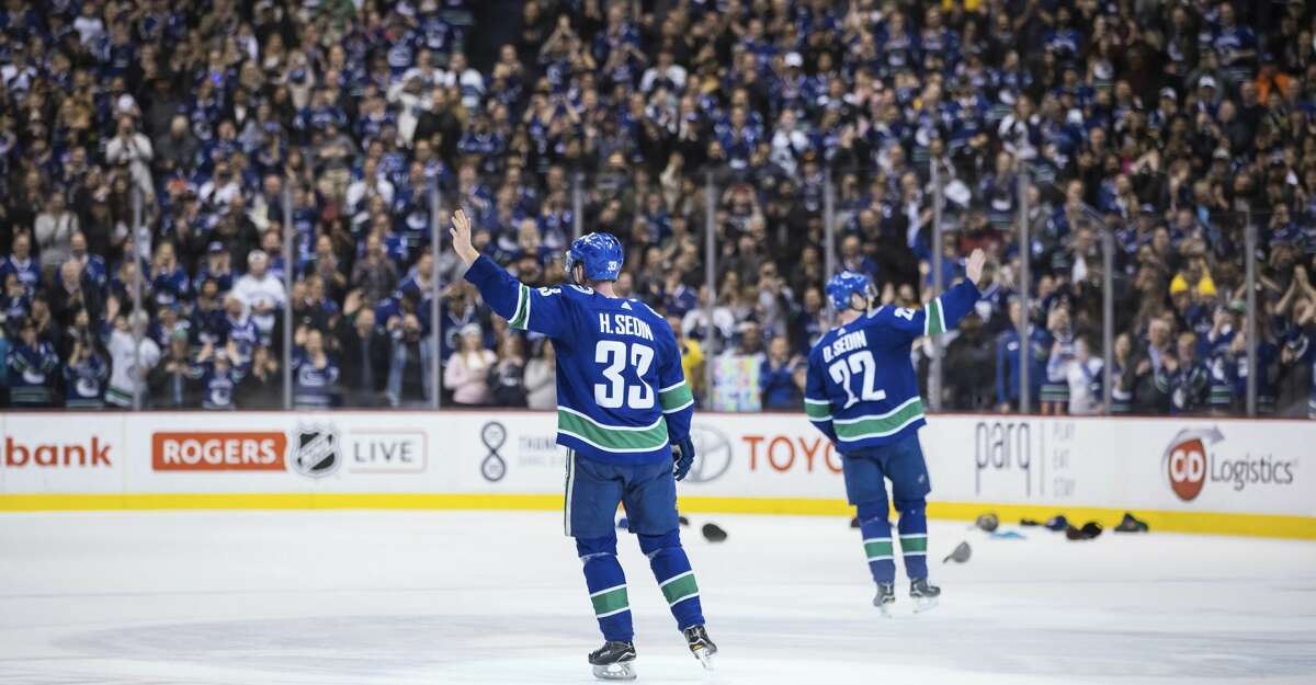 Vancouver Canucks' Henrik Sedin, left, and his twin brother, Daniel Sedin, wave to the crowd after the Canucks defeated the Arizona Coyotes 4-3 in the brothers' last home NHL hockey game, Thursday, April 5, 2018, in Vancouver, British Columbia. (Darryl Dyck/The Canadian Press via AP)