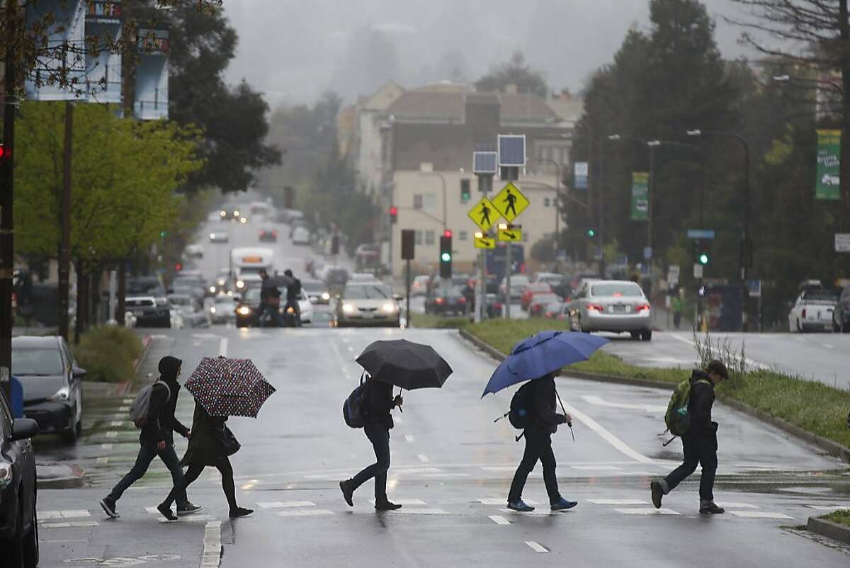 Pedestrians armed with umbrellas cross Oxford Street in Berkeley, Calif. on Friday, April 6, 2018.
