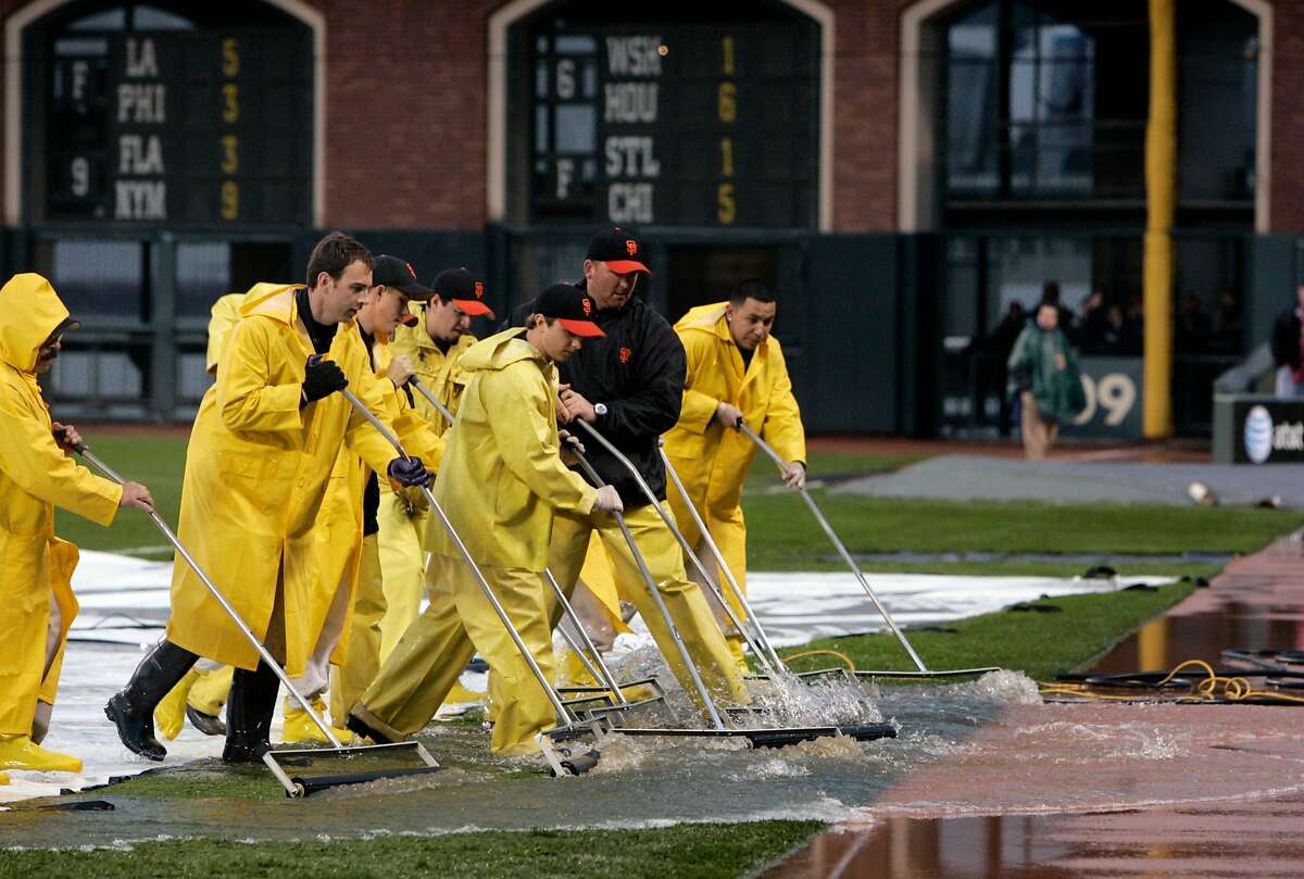 Groundskeepers remove rain water from the field and tarp which has delayed the start of Friday's game. The San Francisco Giants vs. the Atlanta Braves at AT&T Park on 4/7/06 in San Francisco, CA. PAUL CHINN/The Chronicle