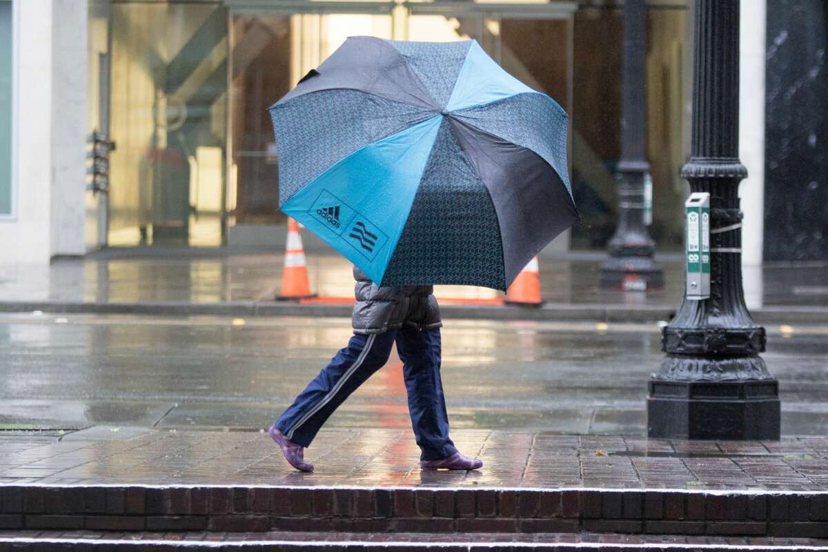 A pedestrian in downtown Oakland uses an umbrella during the rainstorm that hit the Bay Area on Friday April 6, 2018.
