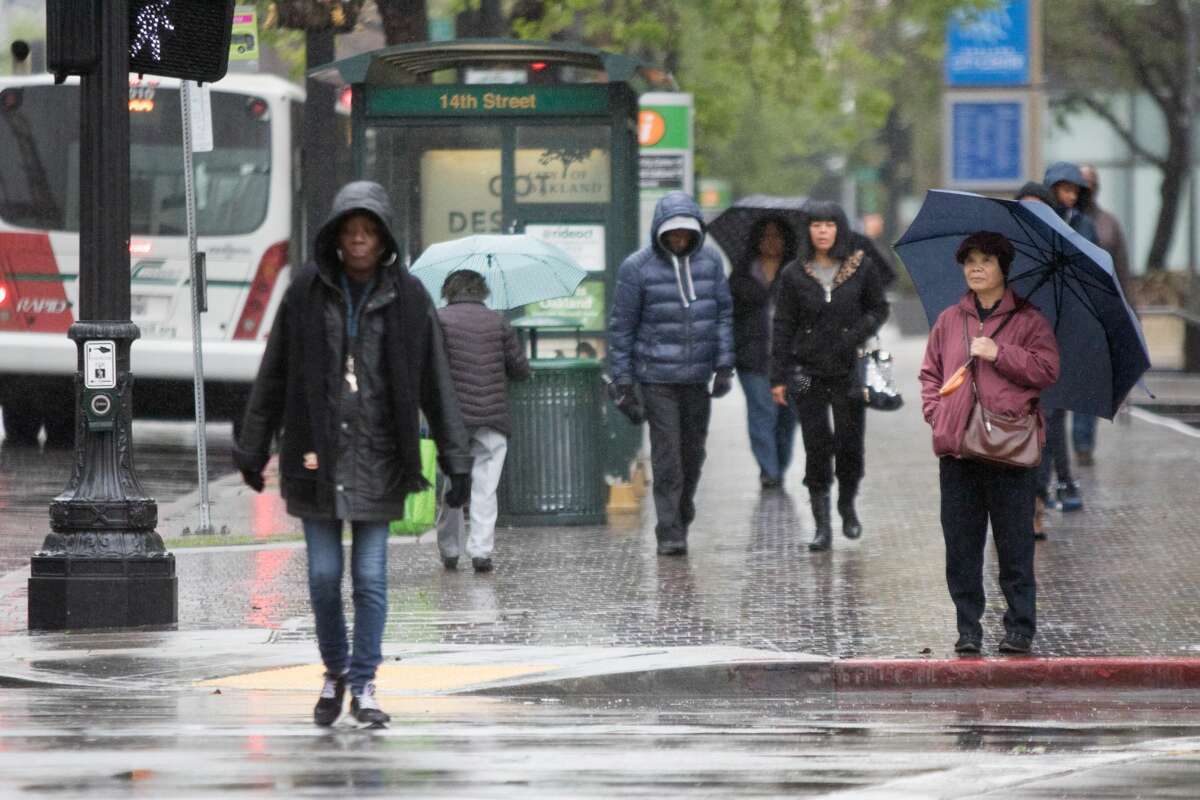 Pedestrians in downtown Oakland make their way during the rainstorm that hit the Bay Area on Friday April 6, 2018.