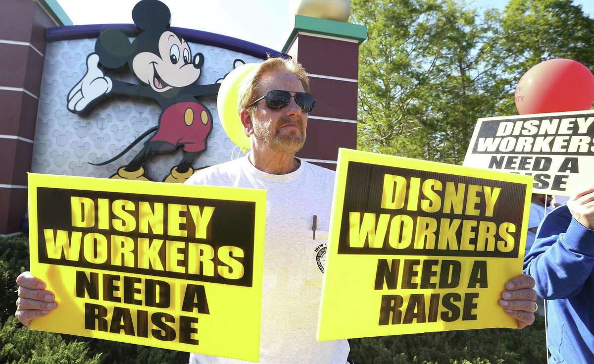 Larry Kidd holds signs in front of Walt Disney World hotel property during a protest last month in Orlando, Fla.