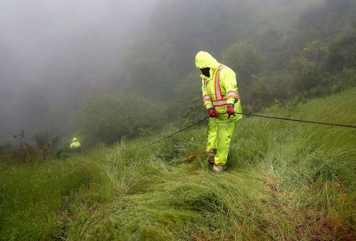 Tow truck personnel descend a steep ravine to retrieve a white Prius on Grizzly Peak Boulevard in Oakland, Calif. on Friday, April 6, 2018 which was discovered about 400 feet down the hill and reportedly belongs to a woman reported missing earlier this week.