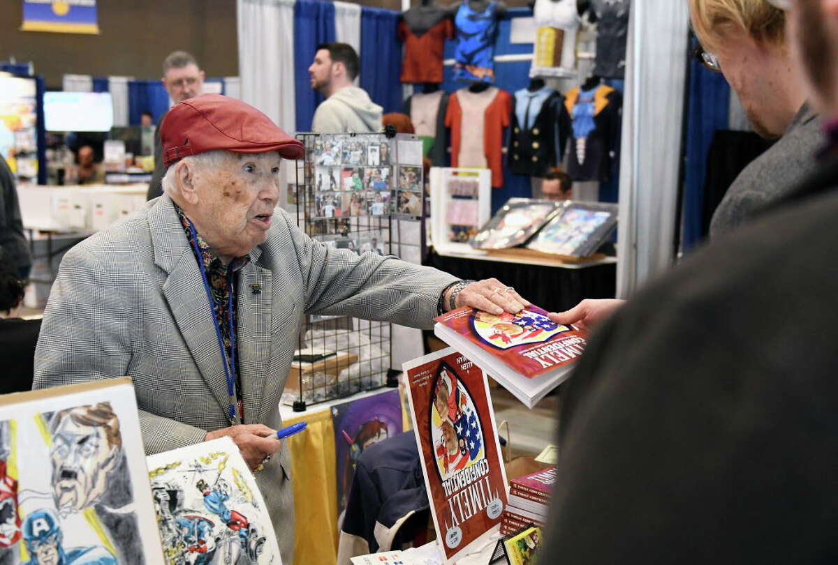 Comic illustrator Allen Bellman, autographs a book for a fan during the Empire State Comic Con festival Saturday, April 7, 2018 in Albany, N.Y.