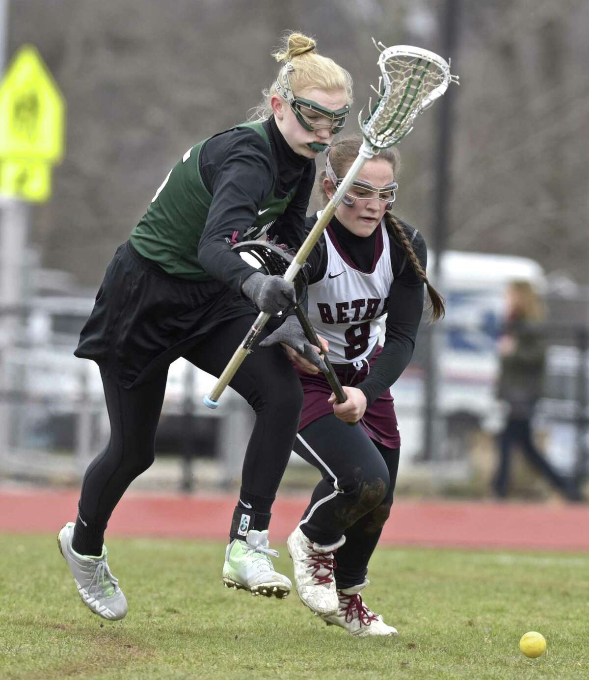 New Milford's Taylor Kersten (15) and Bethel's Christiana Ruiz (8) fight for the ball in the girls lacrosse game between New Milford and Bethel high schools, Saturday, April 7, 2018, at Bethel High School, Bethel, Conn.