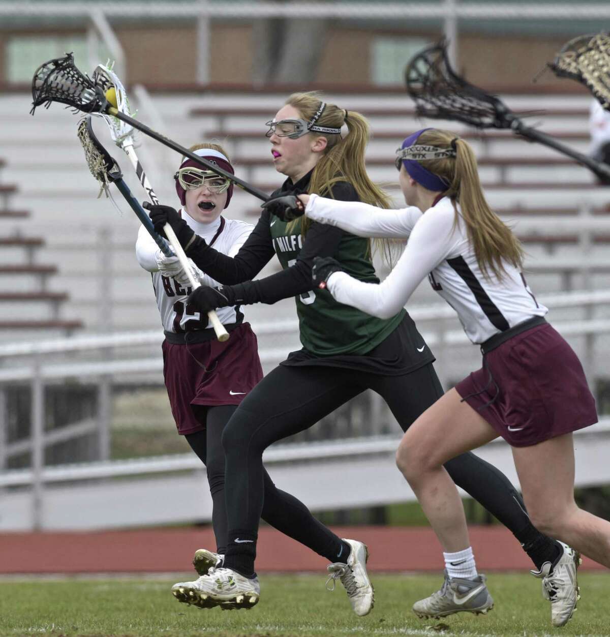 New Milford's Kelsie Baxter (9) squeezes between Bethel's Caroline Nordmann (12) and Victoria Gracy (2) to score a goal in the girls lacrosse game between New Milford and Bethel high schools, Saturday, April 7, 2018, at Bethel High School, Bethel, Conn.