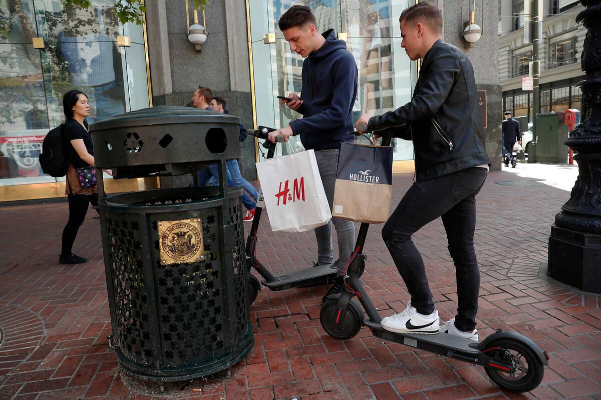Leo Dubler, (left) and Bastien Ruch, visiting from Switzerland check out two Bird scooters for the first time, along Market st. in San Francisco.